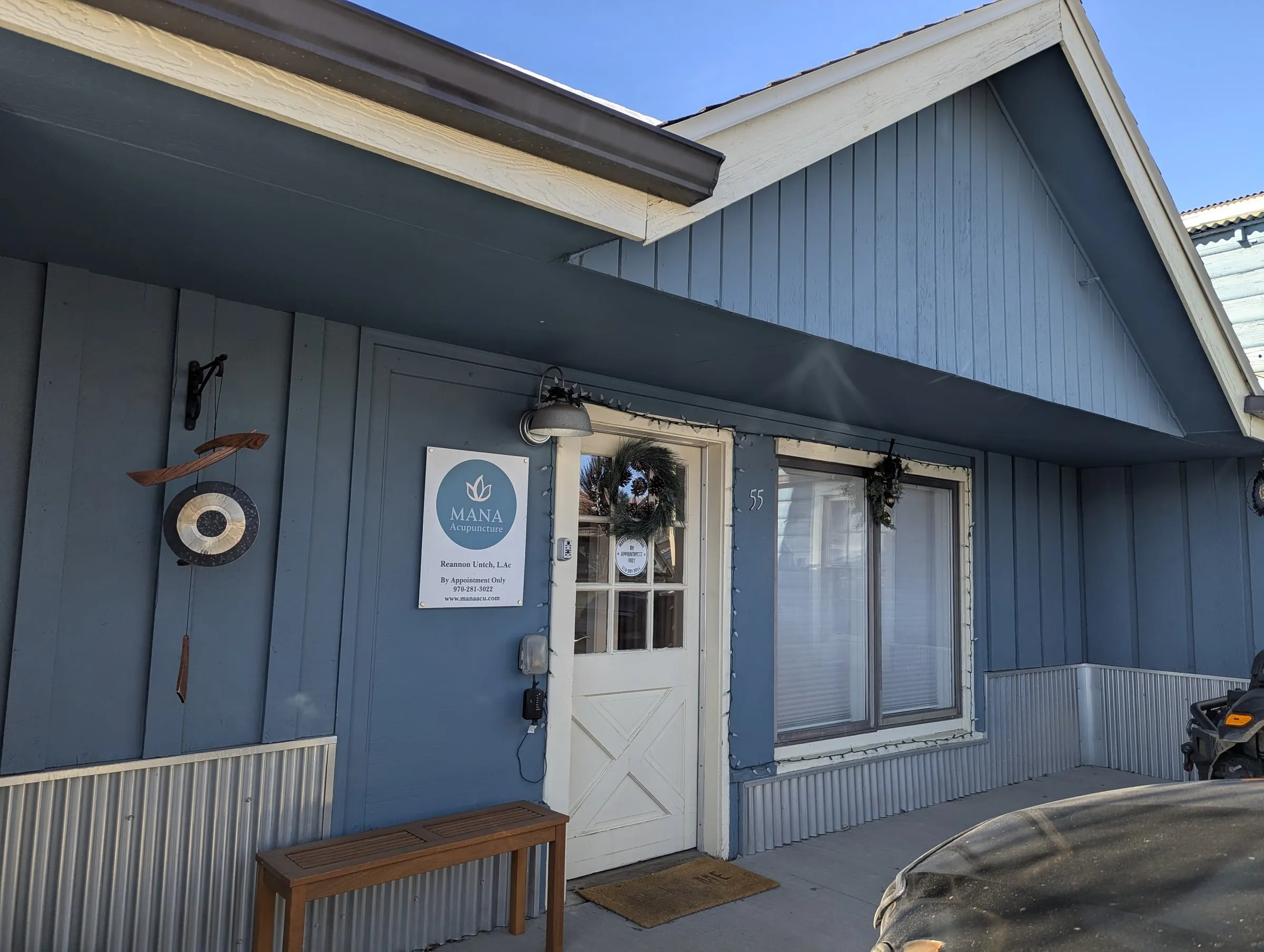 Exterior of Mana Acupuncture at 55 1st St, Granby, Colorado — a blue board-and-batten storefront with the MANA Acupuncture sign