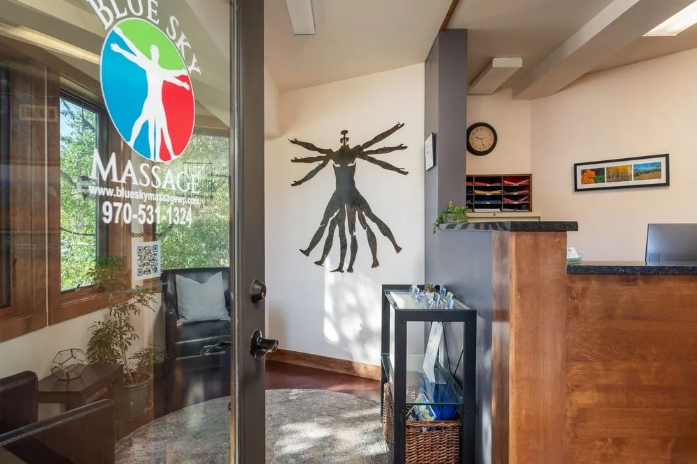 Reception entrance at Blue Sky Massage in Winter Park, Colorado — glass door with the Blue Sky Massage logo and warm wood reception desk